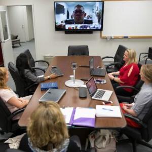 Professor delivering lecture via skype to students in a conference room